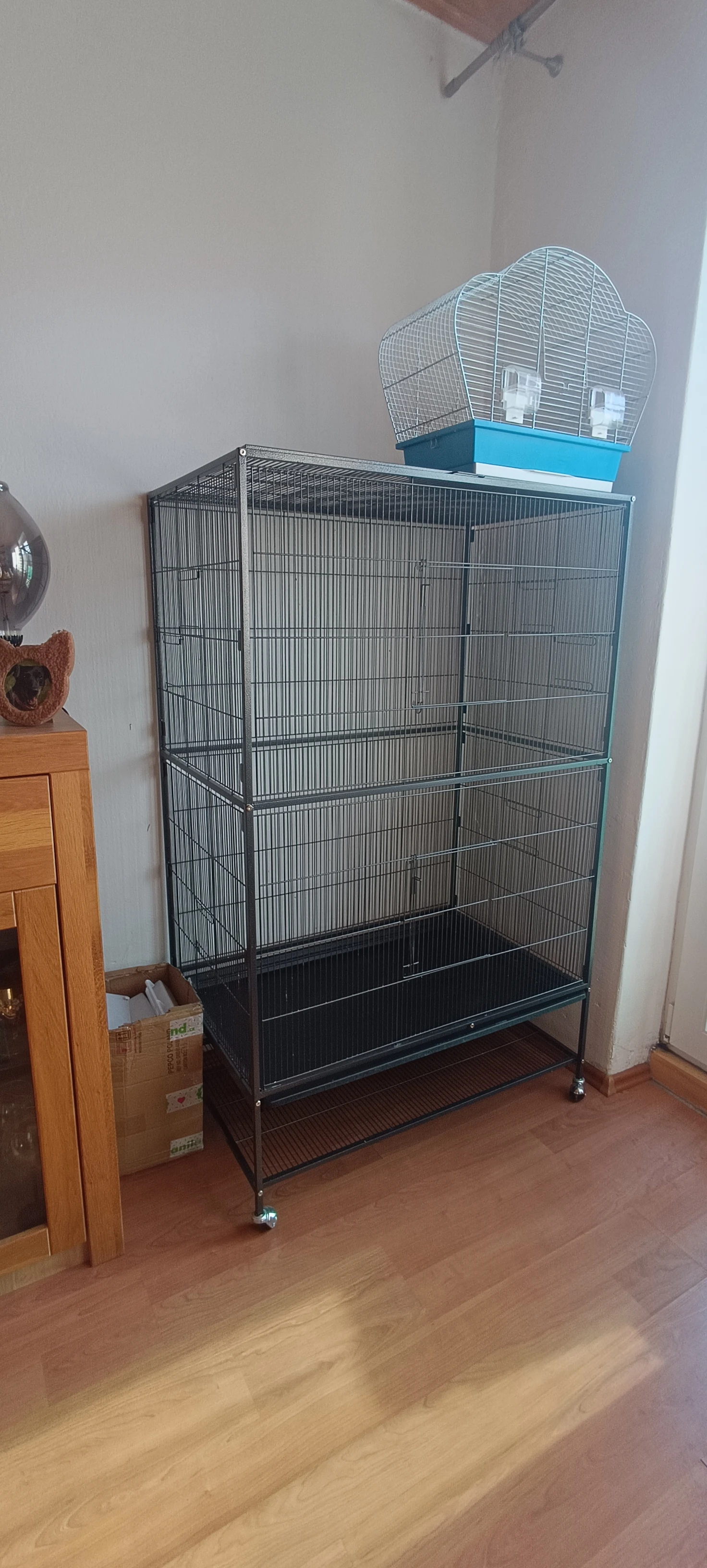 Velká ptačí klec, malá klec, bidýlka a zbytky krmiva